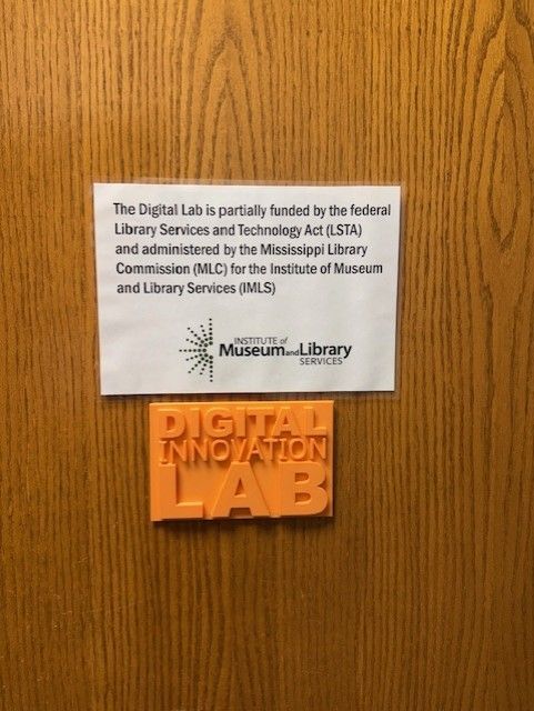 Wooden door with a white Digital Library sign above an orange “DIGITAL INNOVATION LAB” plaque.