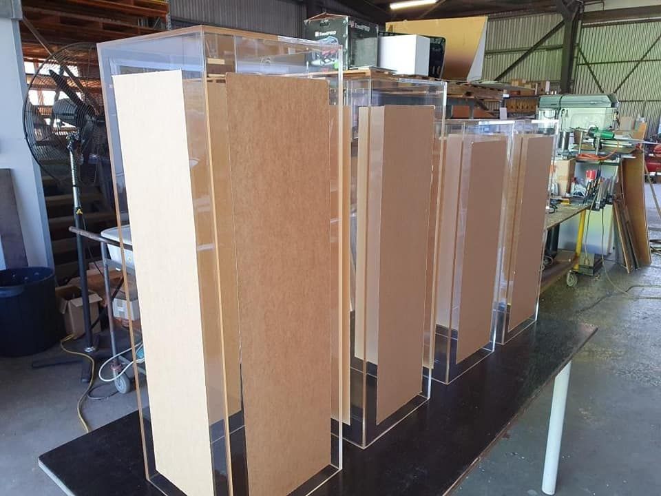 A Row Of Acrylic Boxes Are Sitting On Top Of A Wooden Table — Ram Star Plastics In Winnellie, NT