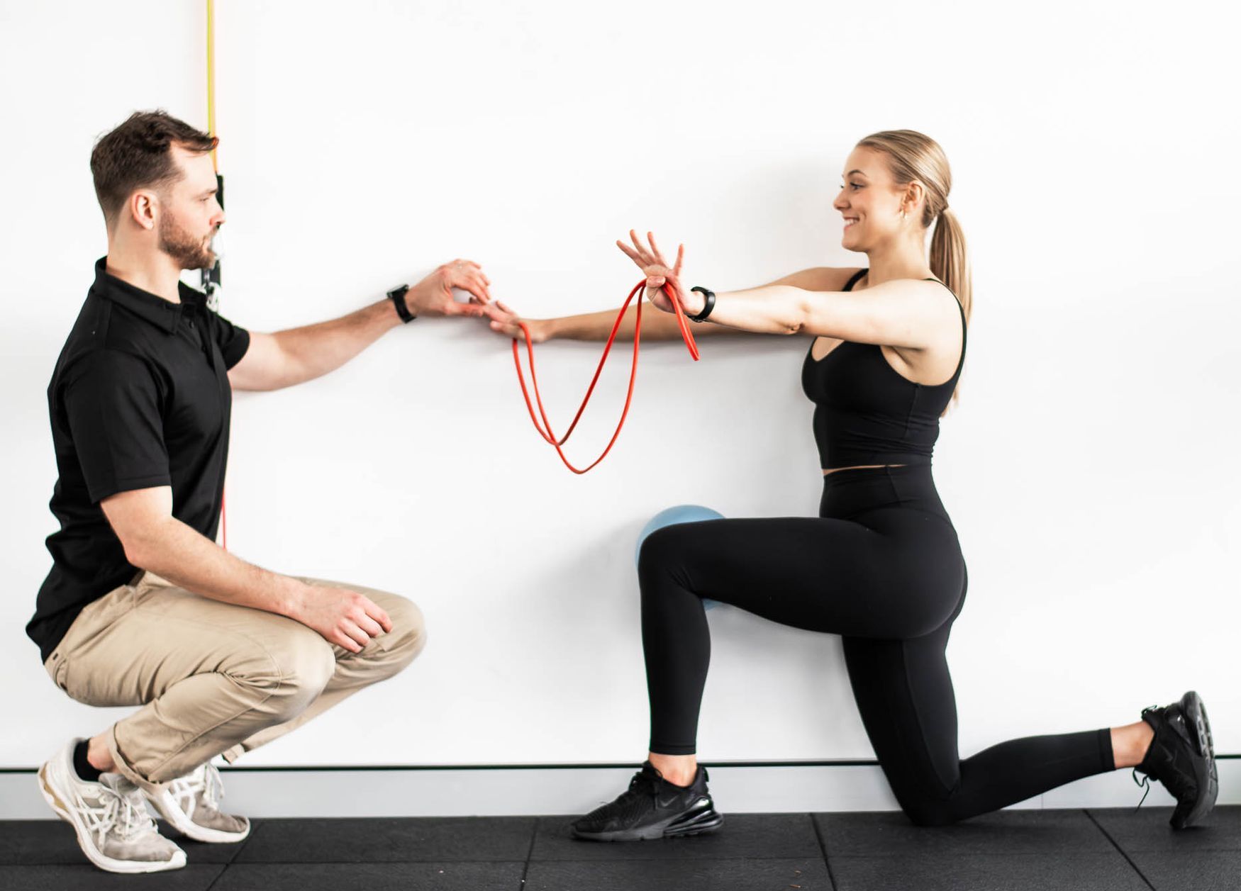 A man is helping a woman do exercises on a mat.