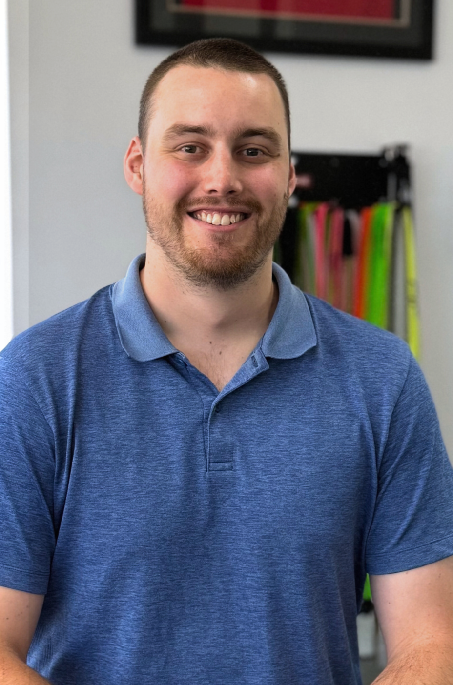 A man wearing a black polo shirt is smiling