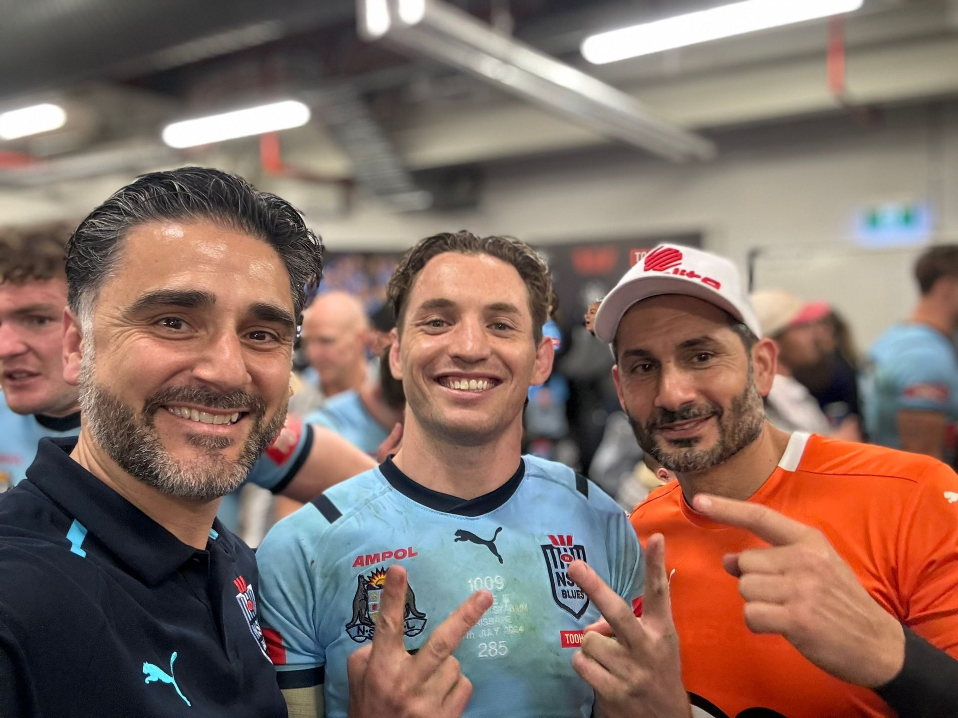 Three men are posing for a picture together in a gym.