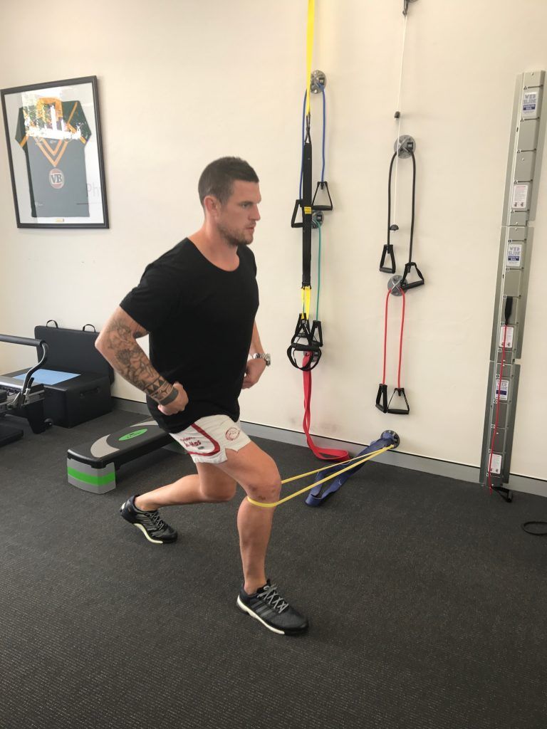 A man is doing lunges with a resistance band in a gym.