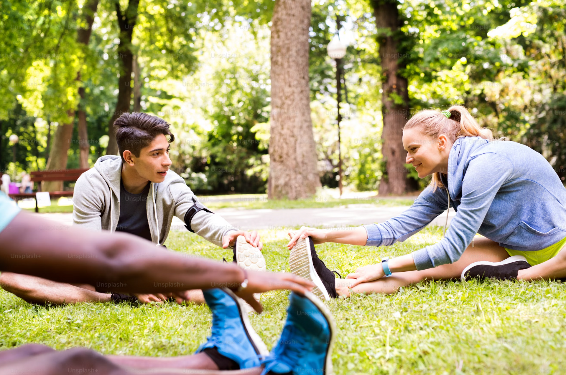 A group of people are stretching their legs in a park 