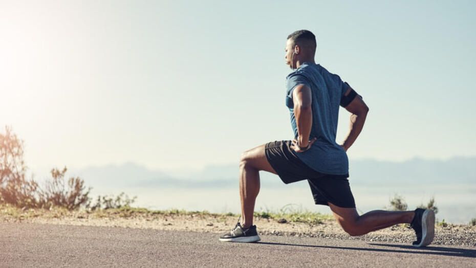 A man is stretching his legs on the side of a road.