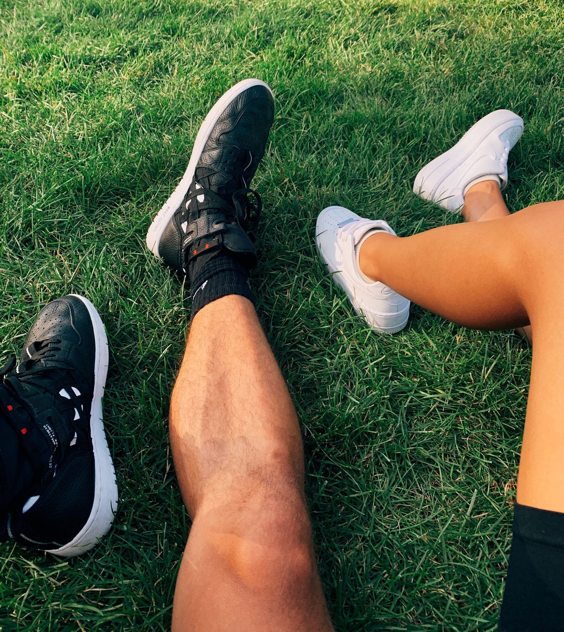 A man and a woman are sitting on the grass with their legs crossed.