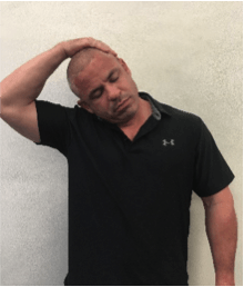 A man in a black under armour shirt stretches his neck