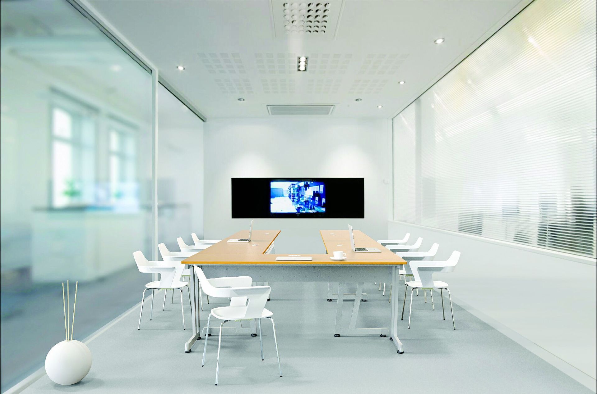 A modern conference room with a large screen, long table, white chairs, and glass walls.