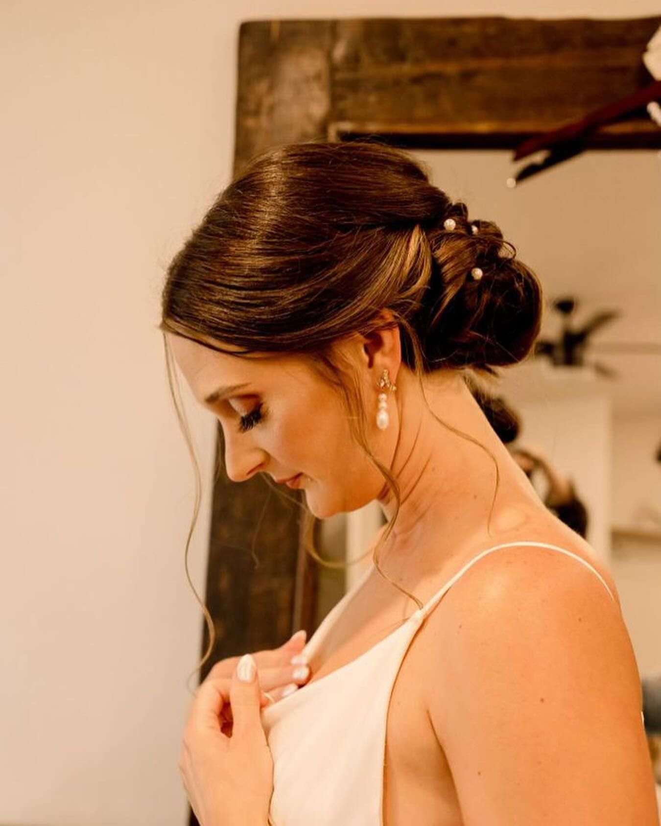 A woman in a white dress is standing in front of a mirror.