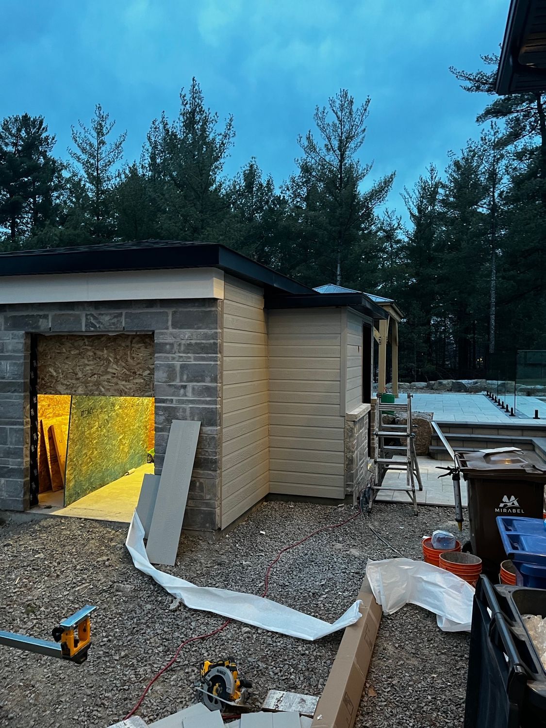 Un bâtiment en brique avec une porte de garage est en construction dans les bois.