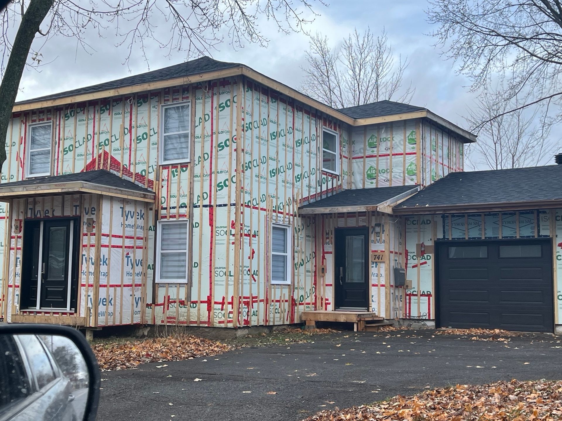 Une maison est en construction avec une voiture garée devant.