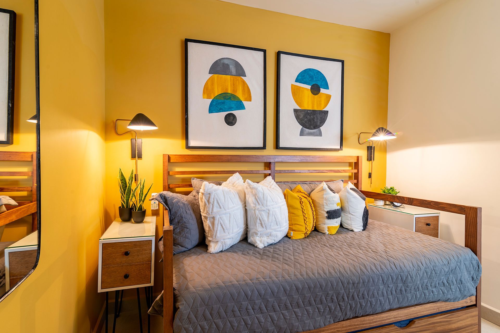 Bedroom with mustard yellow walls, a wooden bed, and framed abstract art.