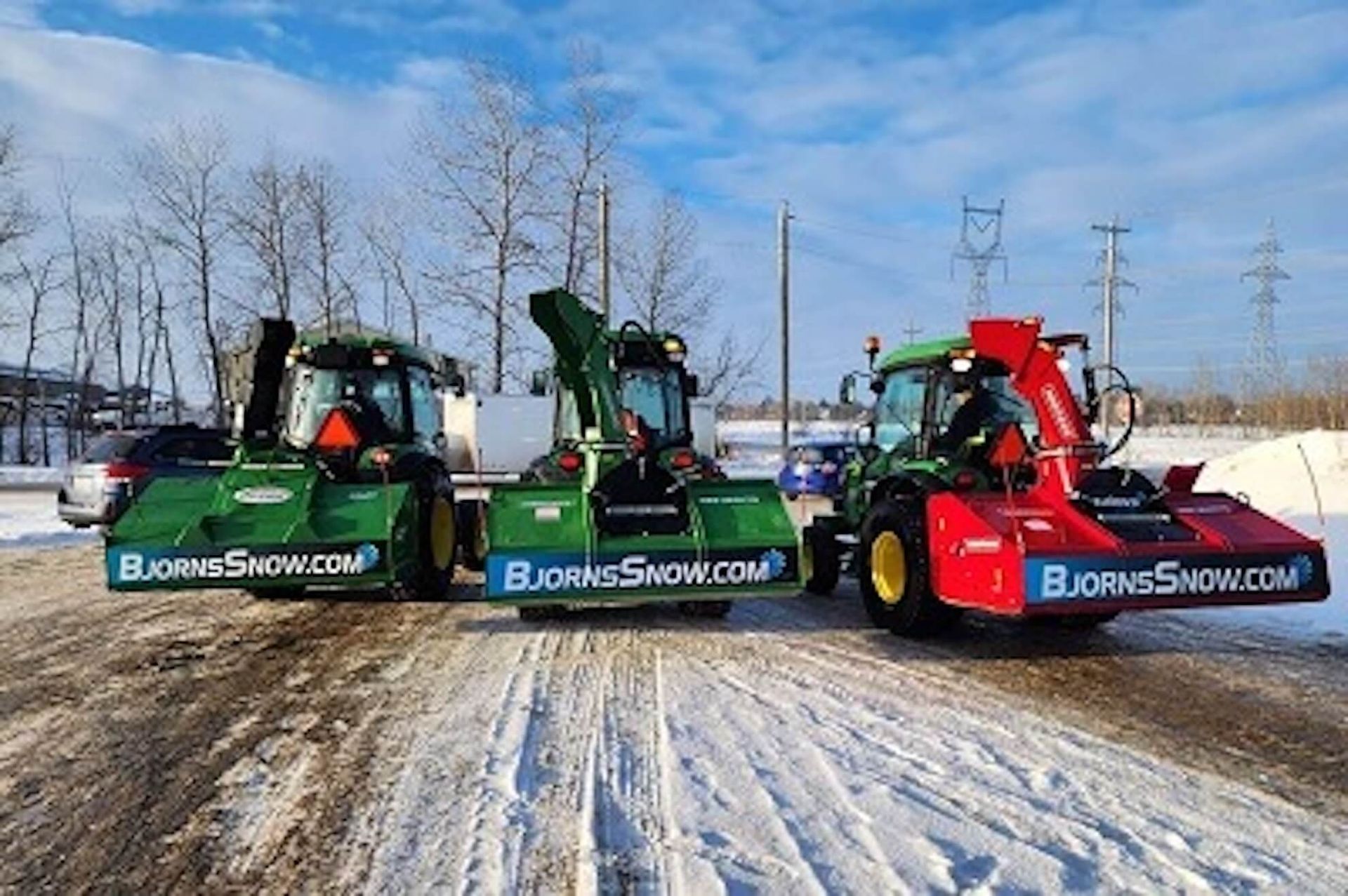 Three snow blowers on a snowy road. All have the company's website on the front.