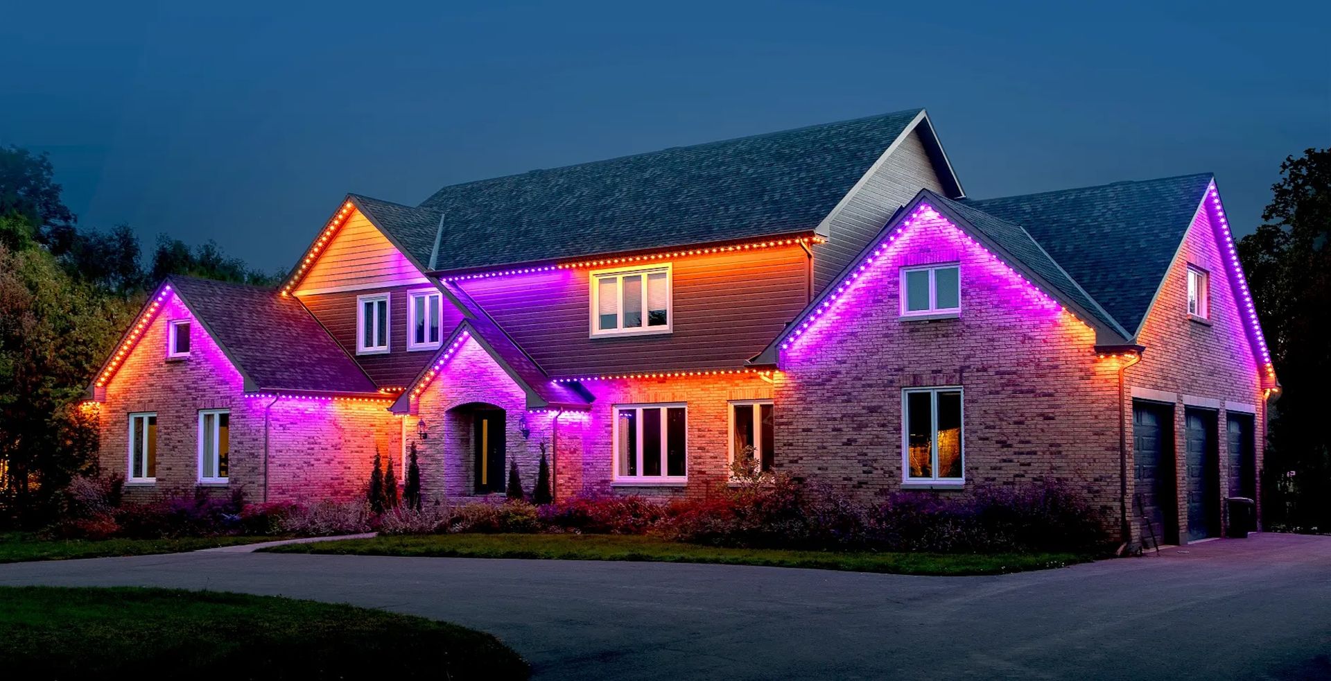 A large brick home at night with vibrant purple LED accent lighting installed along the roofline and window trim.