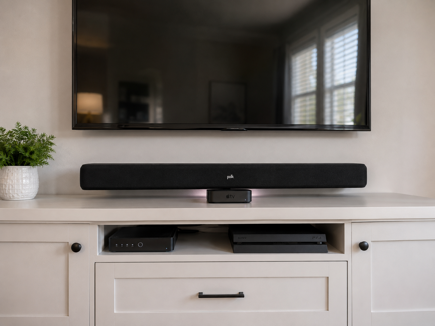 Living room TV with a soundbar on a white media console and a small plant on the left