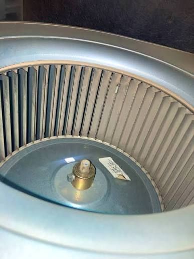 Close-up of a silver metal appliance wheel or fan with vertical slats and a central brass spindle