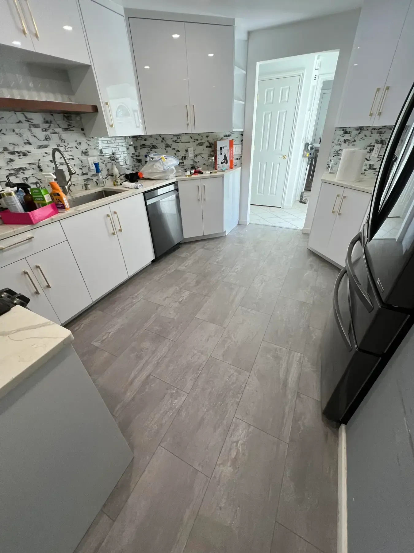 Bright modern kitchen with white cabinets, gray floor, and stainless steel appliances.
