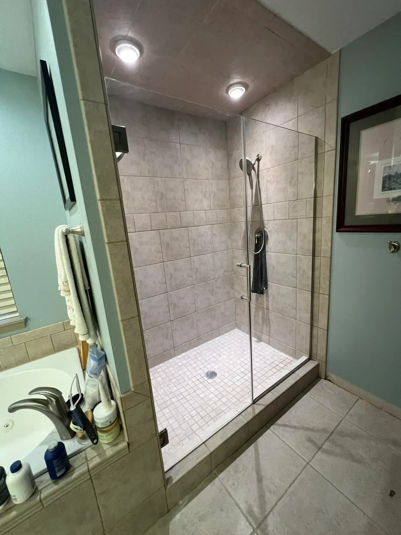 Walk-in shower with glass door, tiled walls, bench, and built-in shelf in a bathroom.