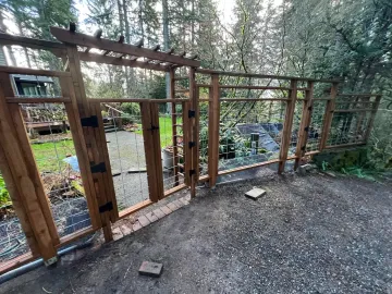 Wooden gate and fence overlooking a forested stream along a gravel path
