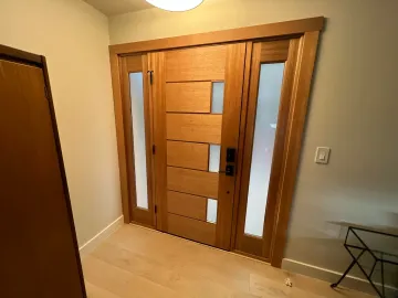 Wooden front door with frosted glass panels in a bright hallway, with a small table on the right.