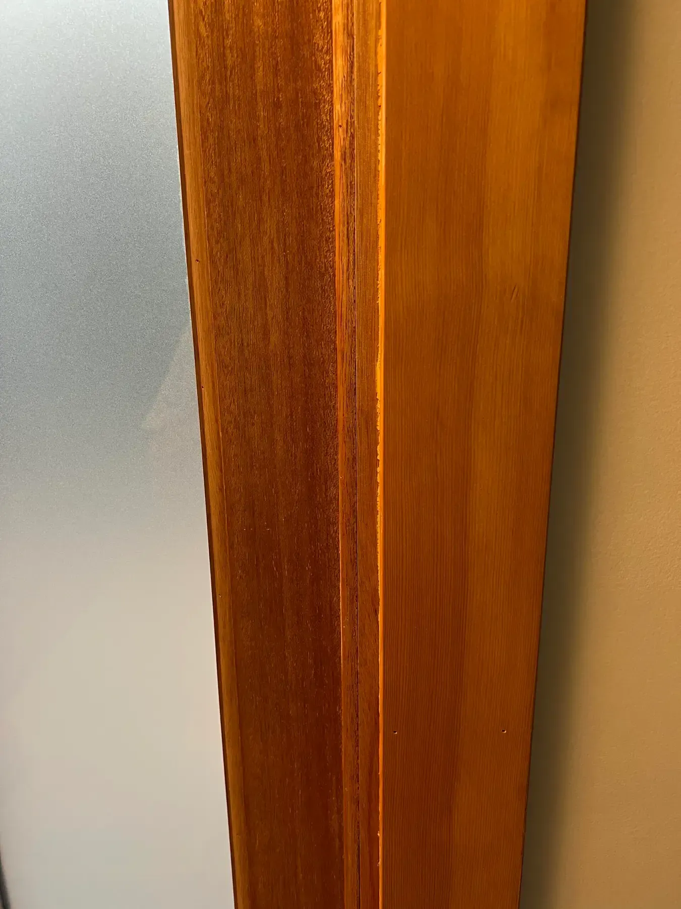 Close-up of a wooden door frame beside frosted glass.