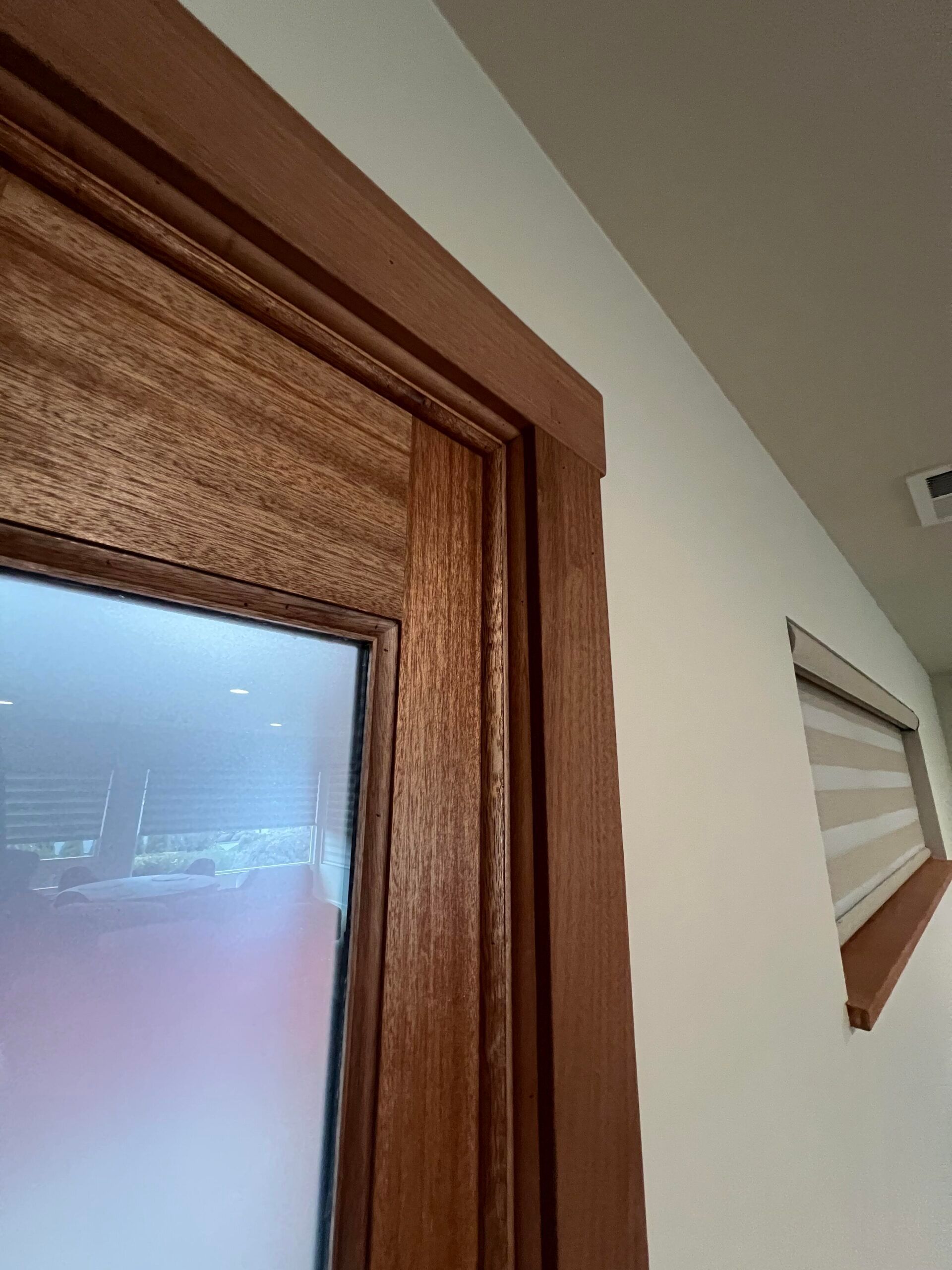 Wood-framed doorway and wall-mounted angled shelf in a beige interior hallway