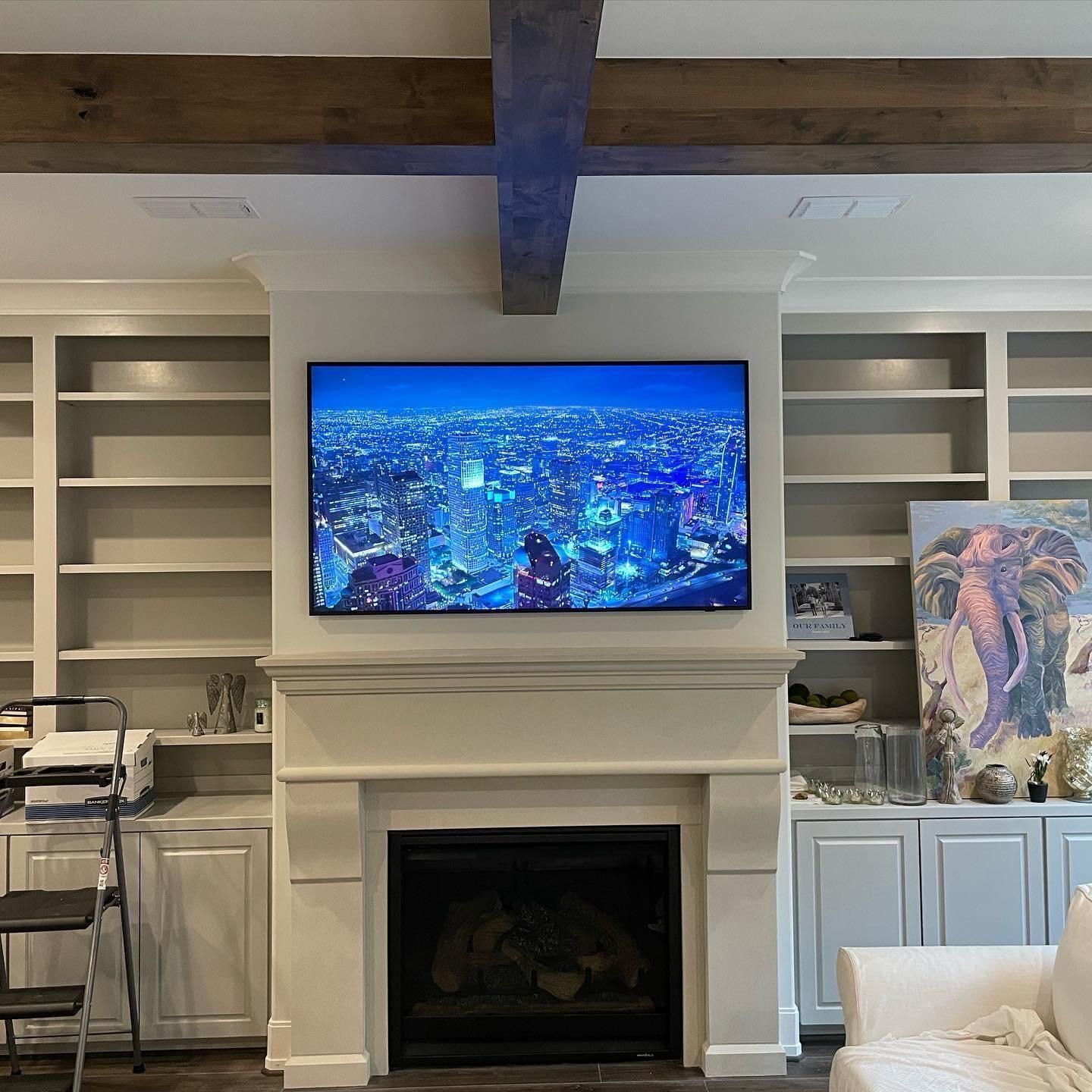 Living room with built-in shelves, fireplace, and wall-mounted TV showing a cityscape at night