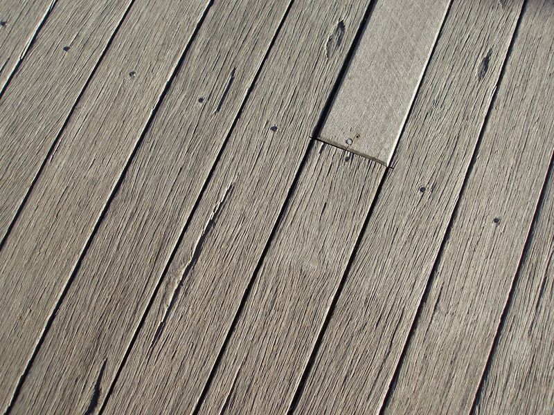 Weathered gray wooden floorboards with one lighter plank section
