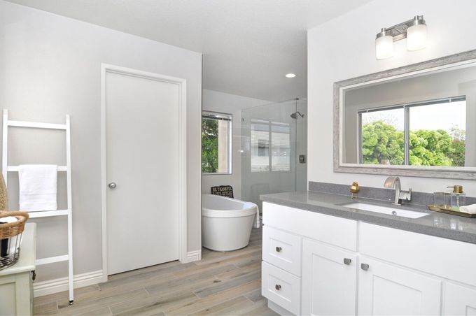 Bright modern bathroom with double vanity, large mirror, and freestanding tub