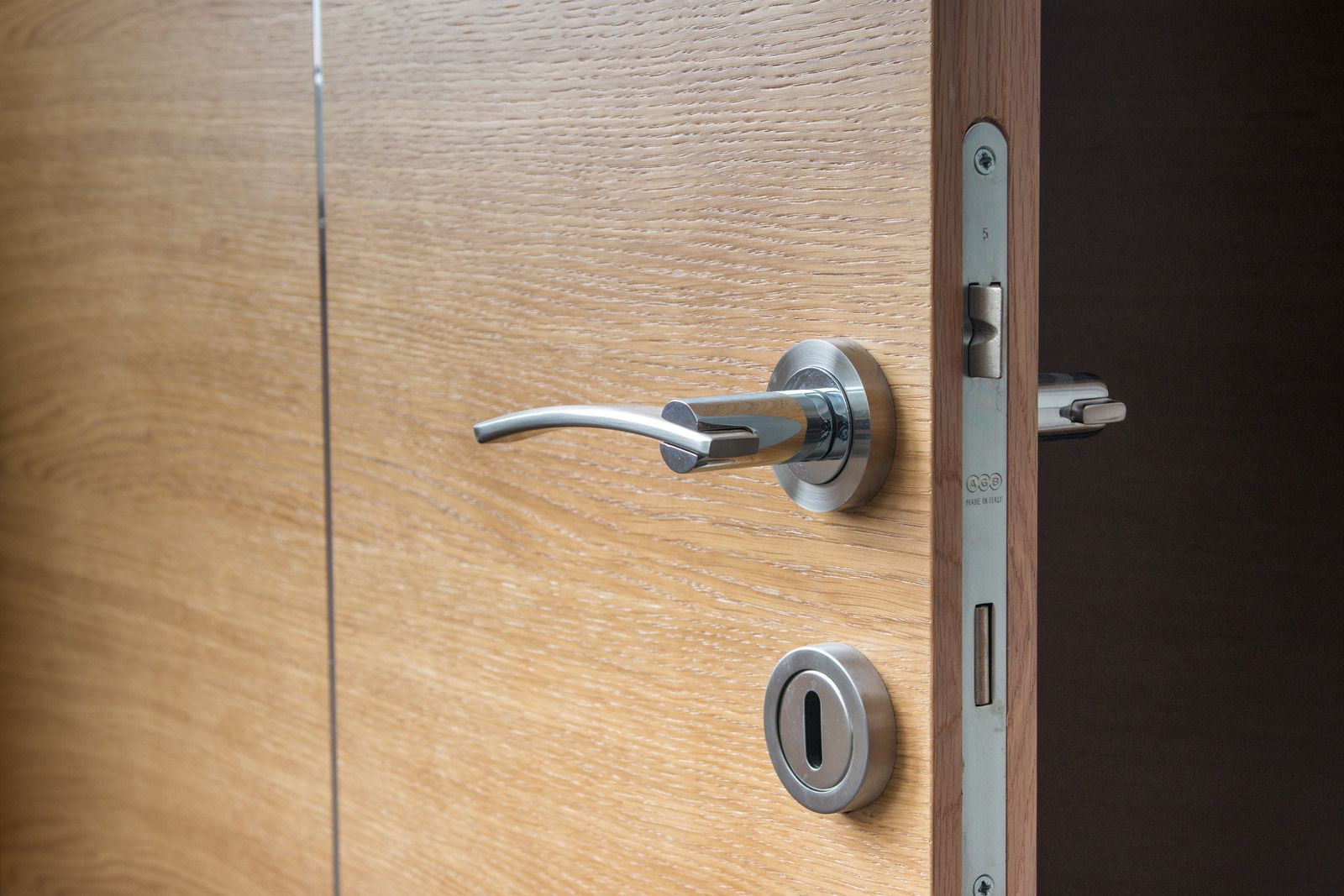 Open wooden door with silver handle and lock, partially ajar.