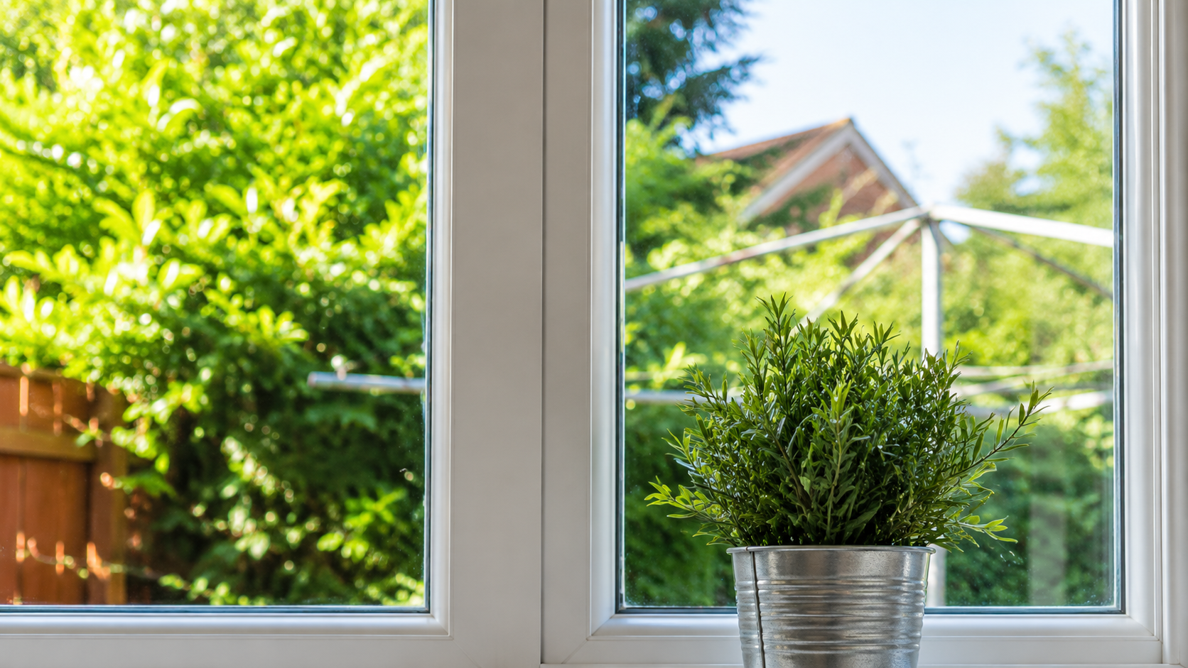 Potted plant on a windowsill with bright green garden view outside