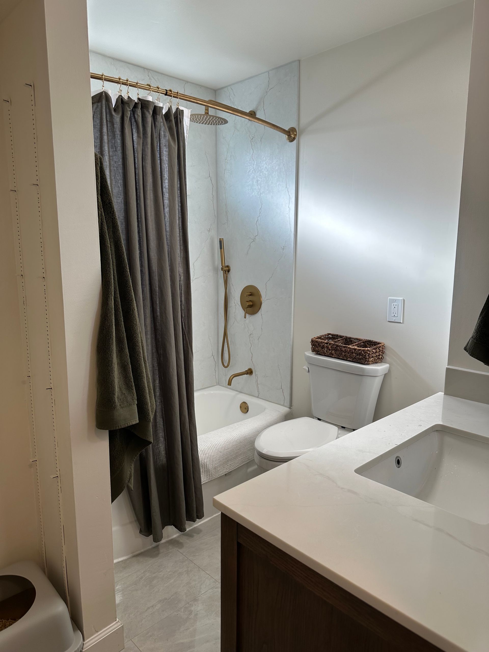 Small bathroom with a shower curtain, toilet, and vanity sink in a bright white interior.
