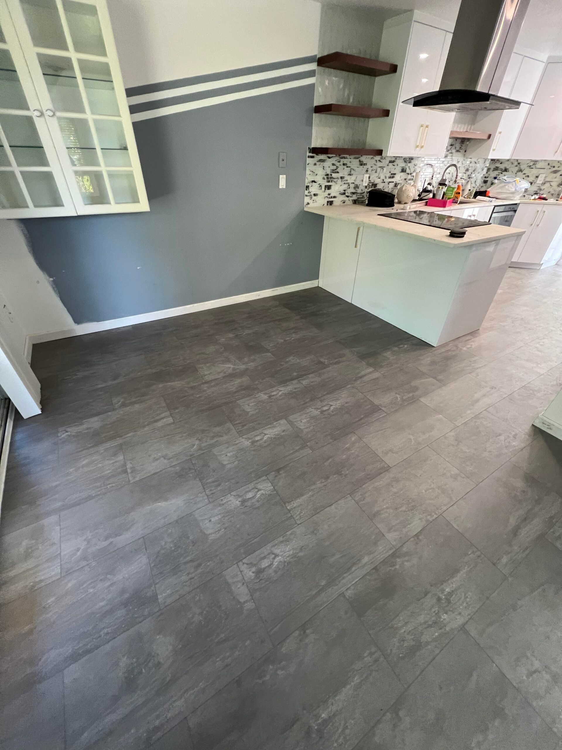 Empty modern kitchen with gray flooring, white cabinets, and a small counter area