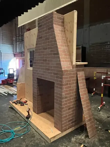 Brick-and-wood wall mockup in a workshop, with a loose brick panel leaning against it