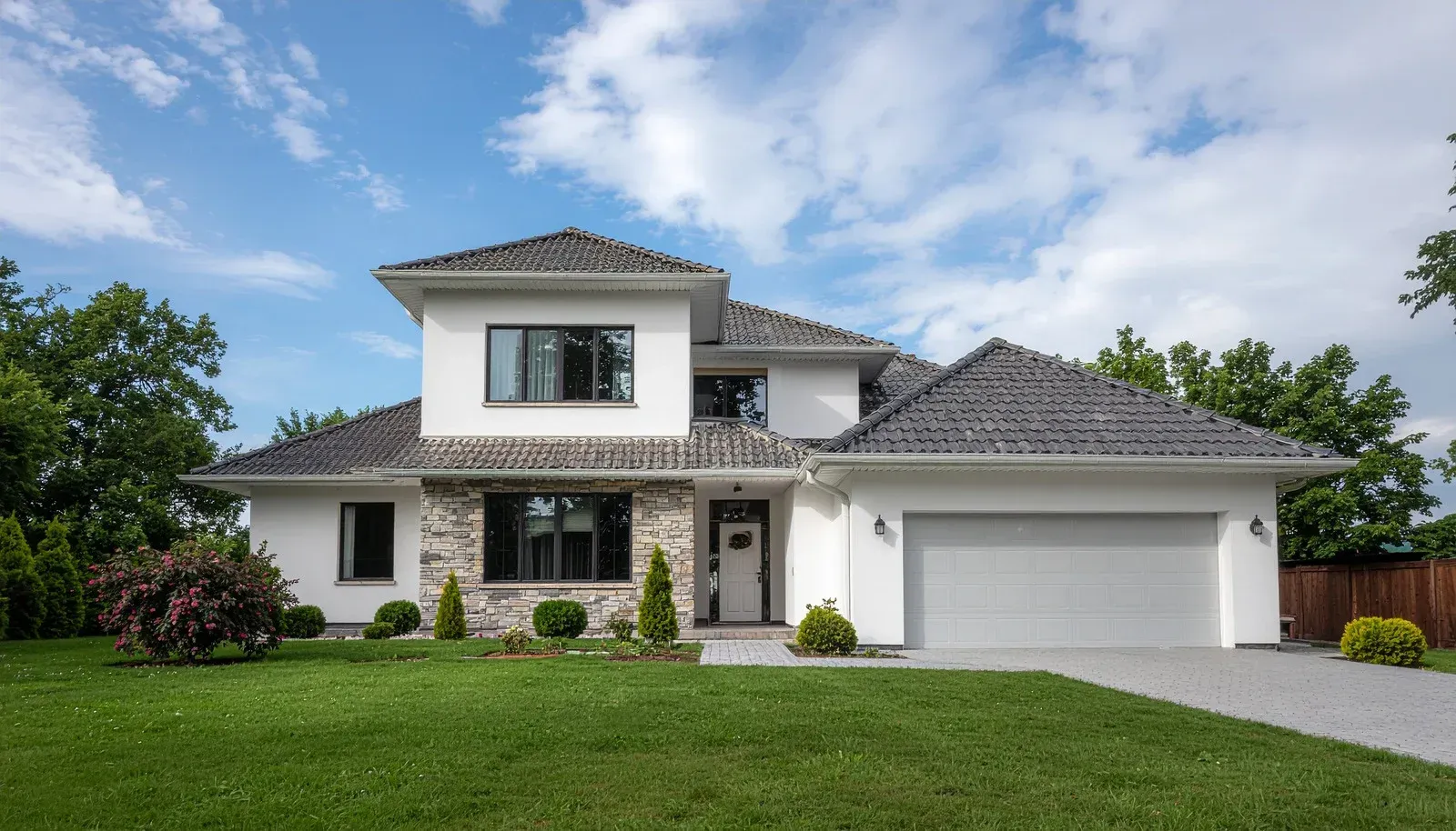 Modern two-story white house with gray roof, front lawn, and attached two-car garage