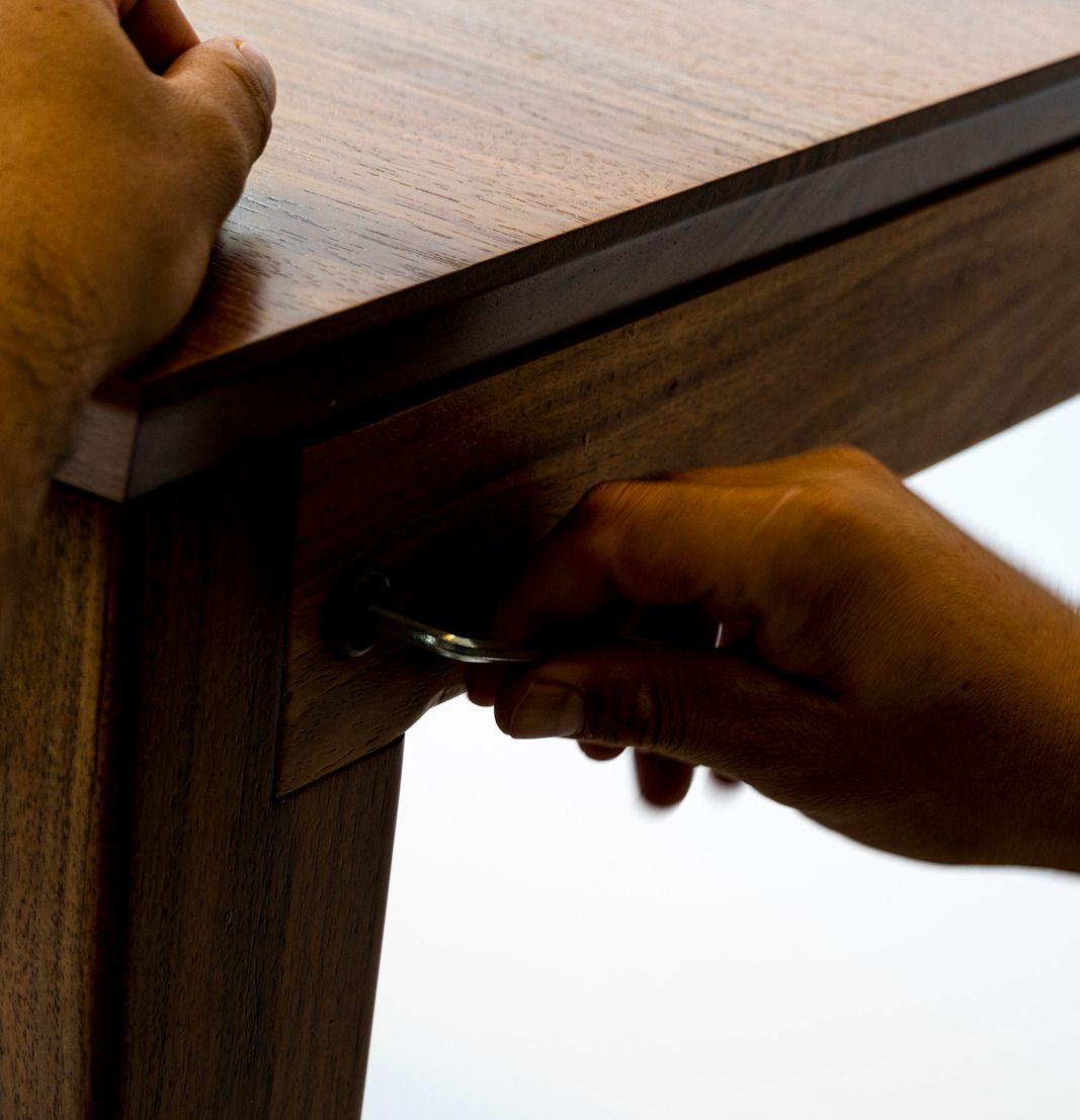 Hands tightening a screw under a wooden table with a screwdriver
