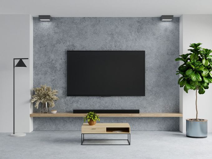 Modern living room with wall-mounted TV, floating shelf, plants, and minimalist gray decor