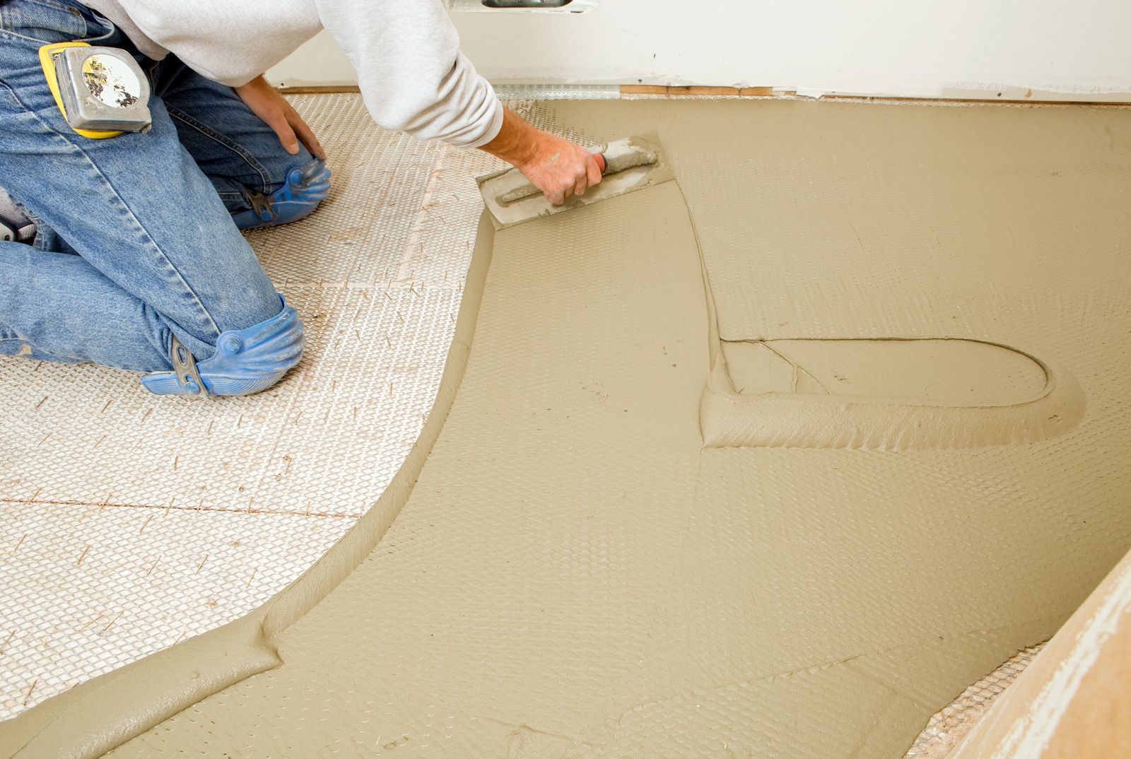 Person smoothing wet concrete with a trowel during floor installation