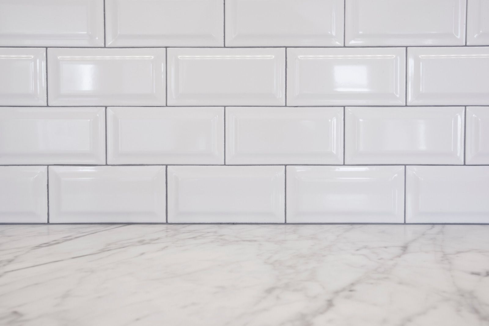 White subway tile backsplash above a light gray marble countertop