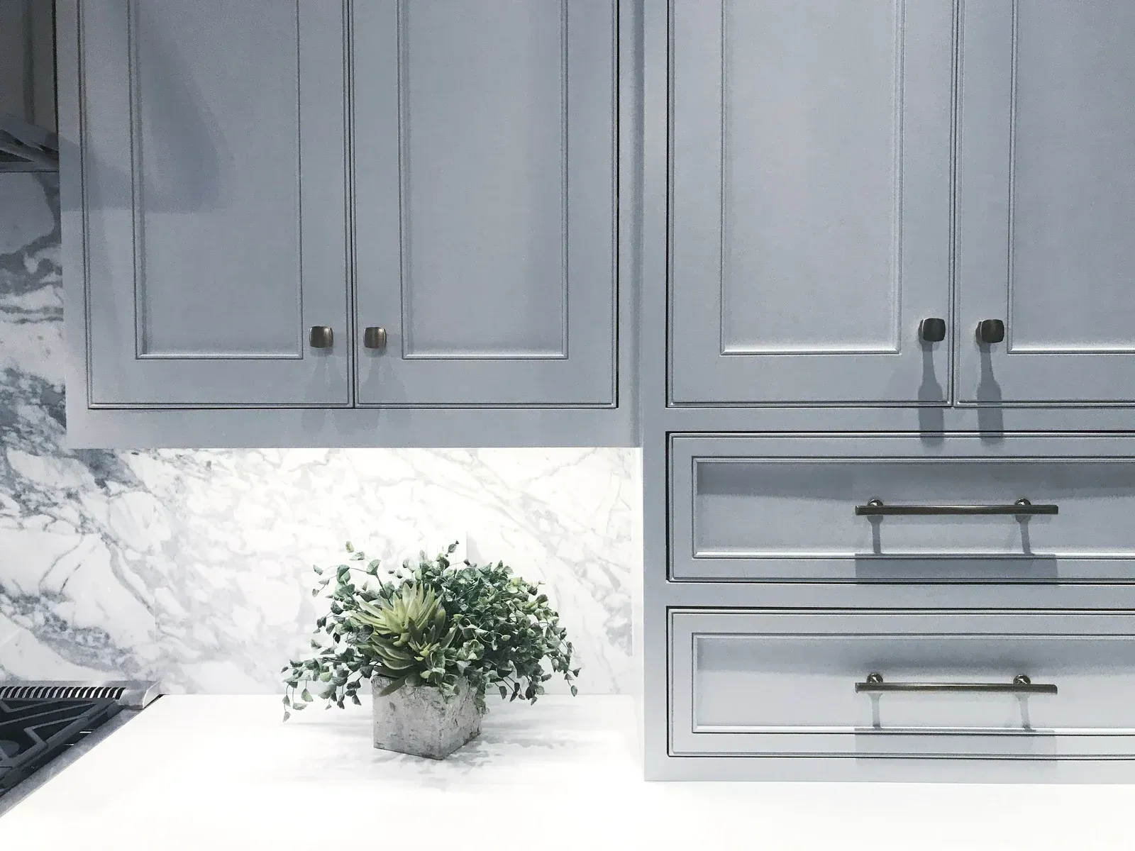 Modern kitchen with gray cabinets, white marble backsplash, and a potted plant on the counter