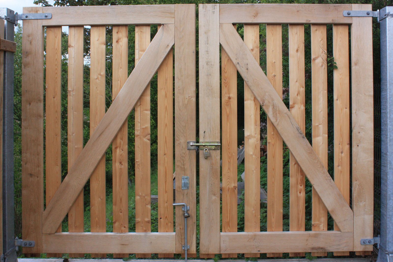 Wooden double gate with diagonal braces and vertical slats, closed with a latch.