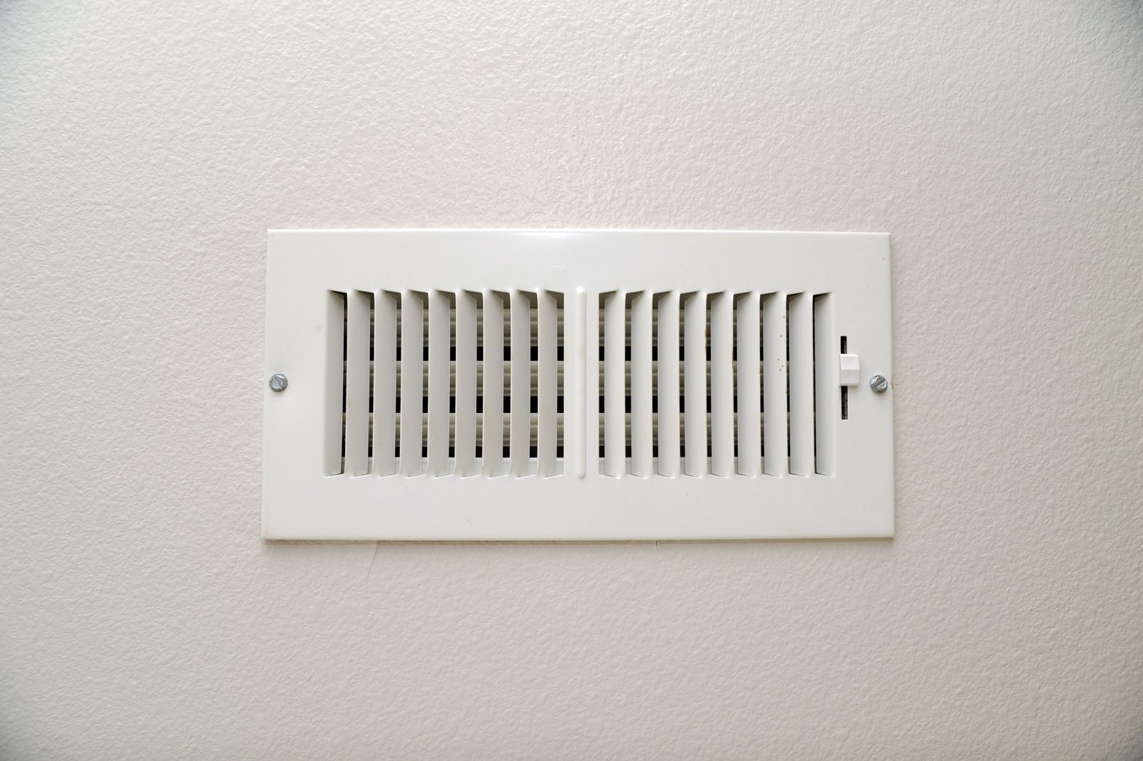 White wall air vent grille with slats and two visible screws