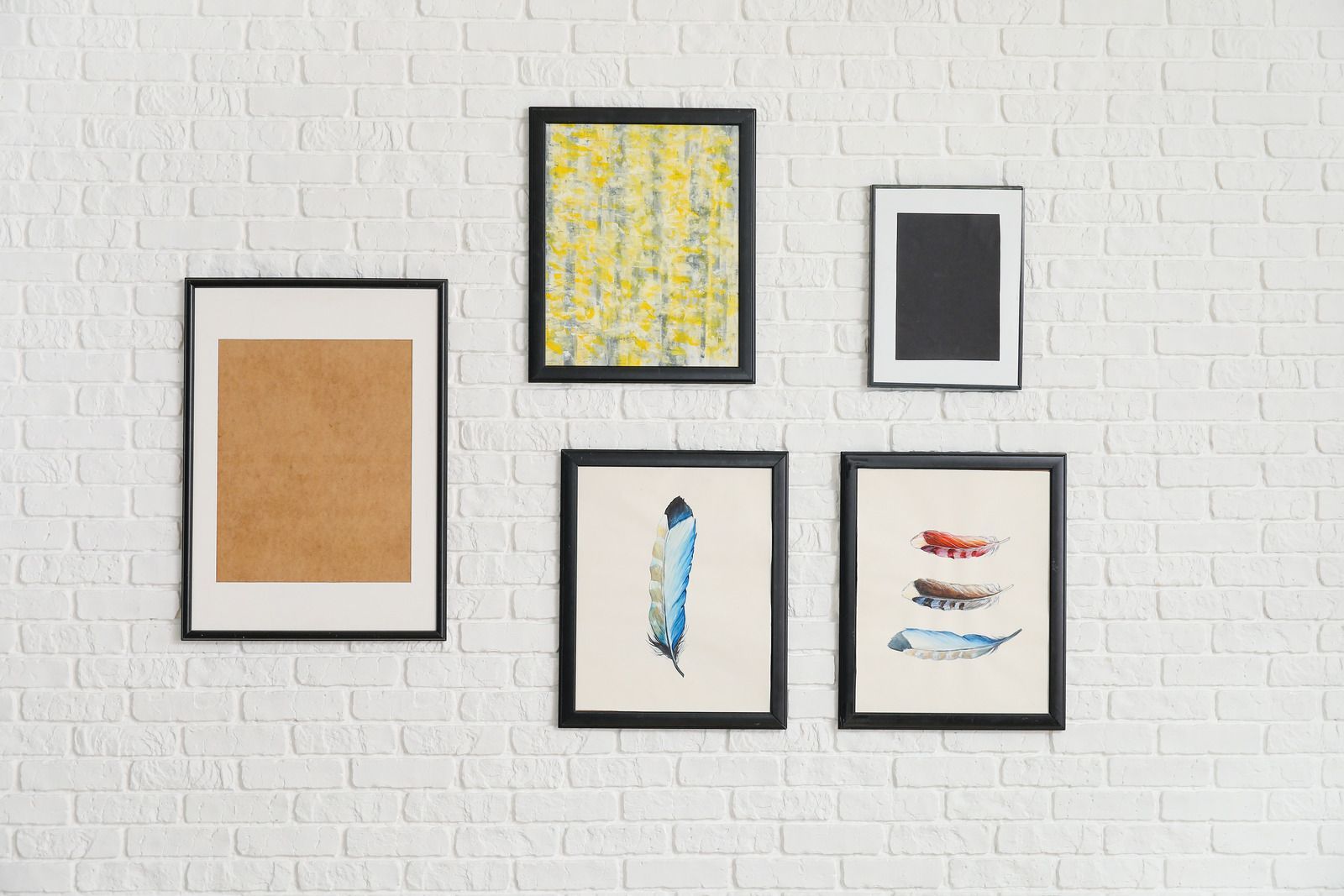 Five framed abstract artworks arranged on a white brick wall.