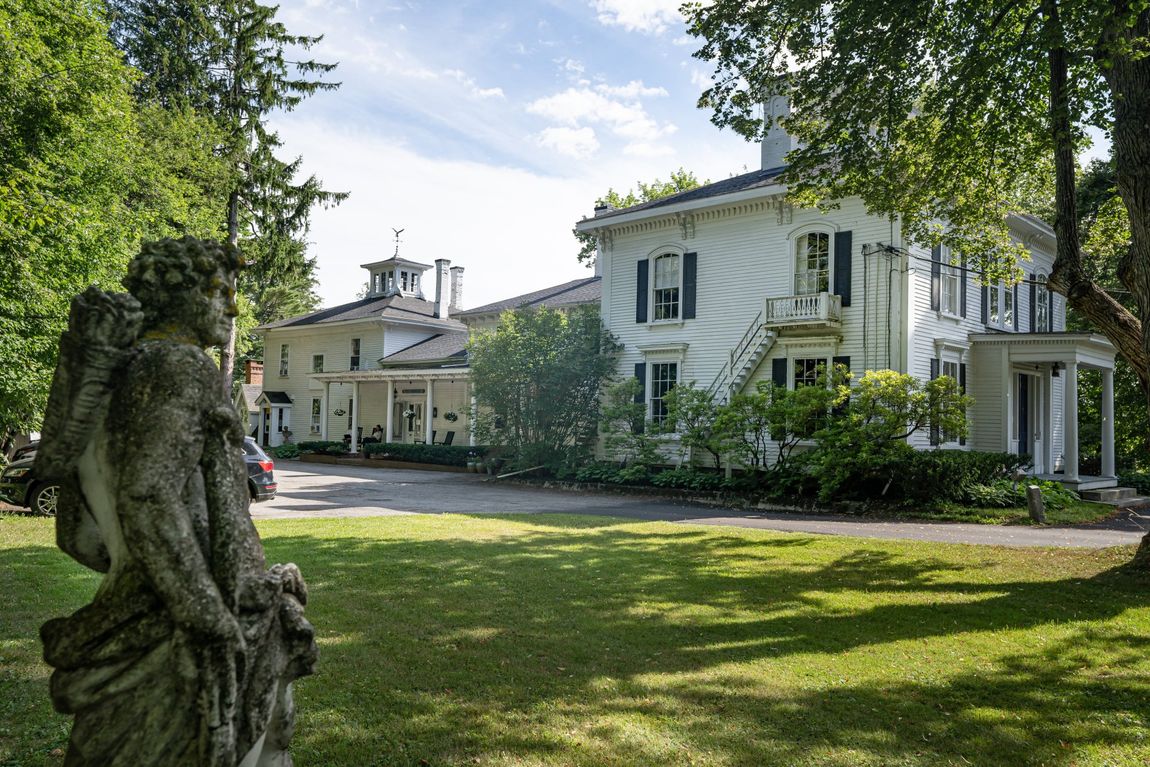 A large white house with a statue in front of it