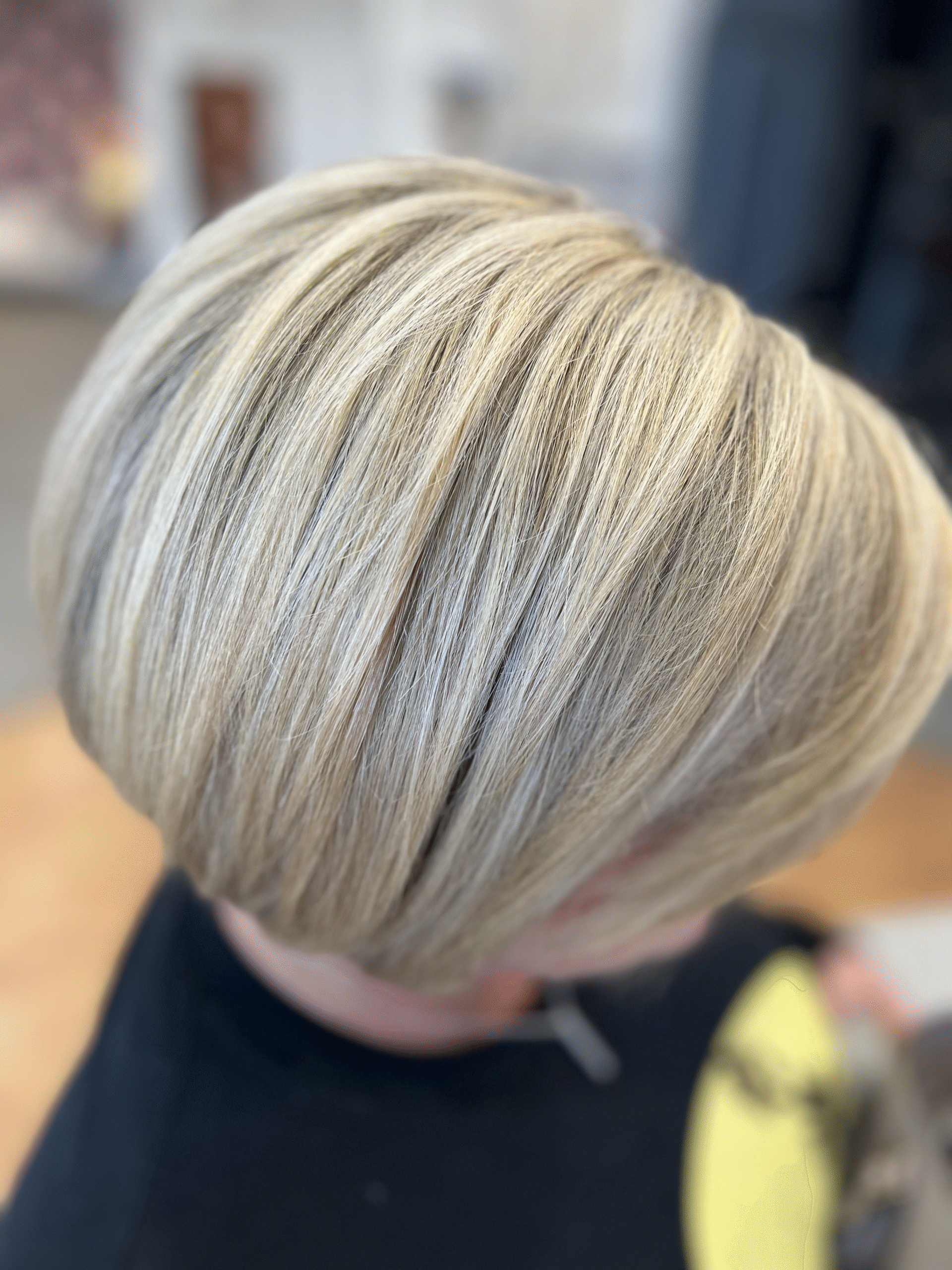 Close-up of a short layered blonde haircut with silver highlights on a salon client