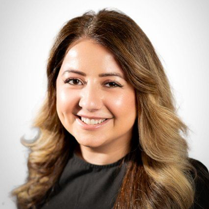 Smiling person with long wavy hair in a black top against a light background