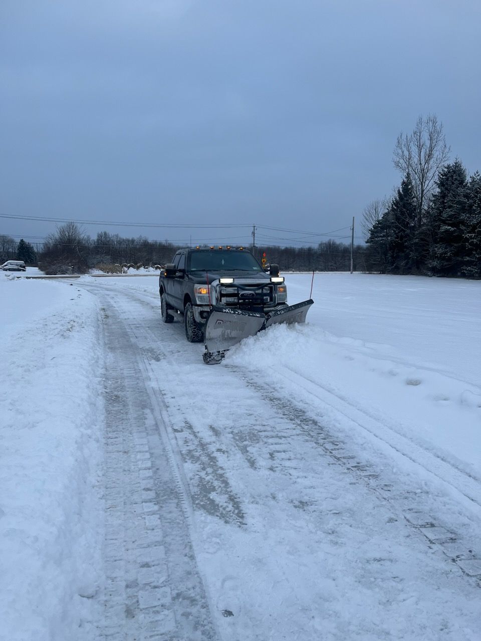 A truck is plowing snow on a snowy road.