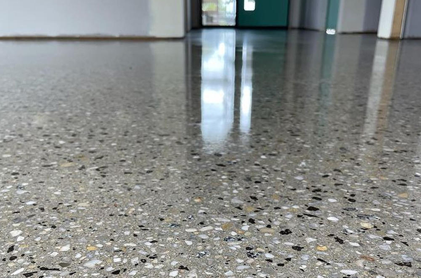 Polished concrete floor with visible aggregate, reflecting a bright room.