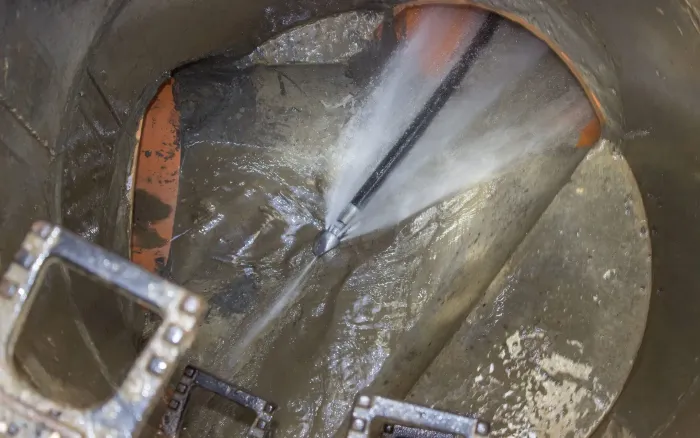 A hose is spraying water into a drain.