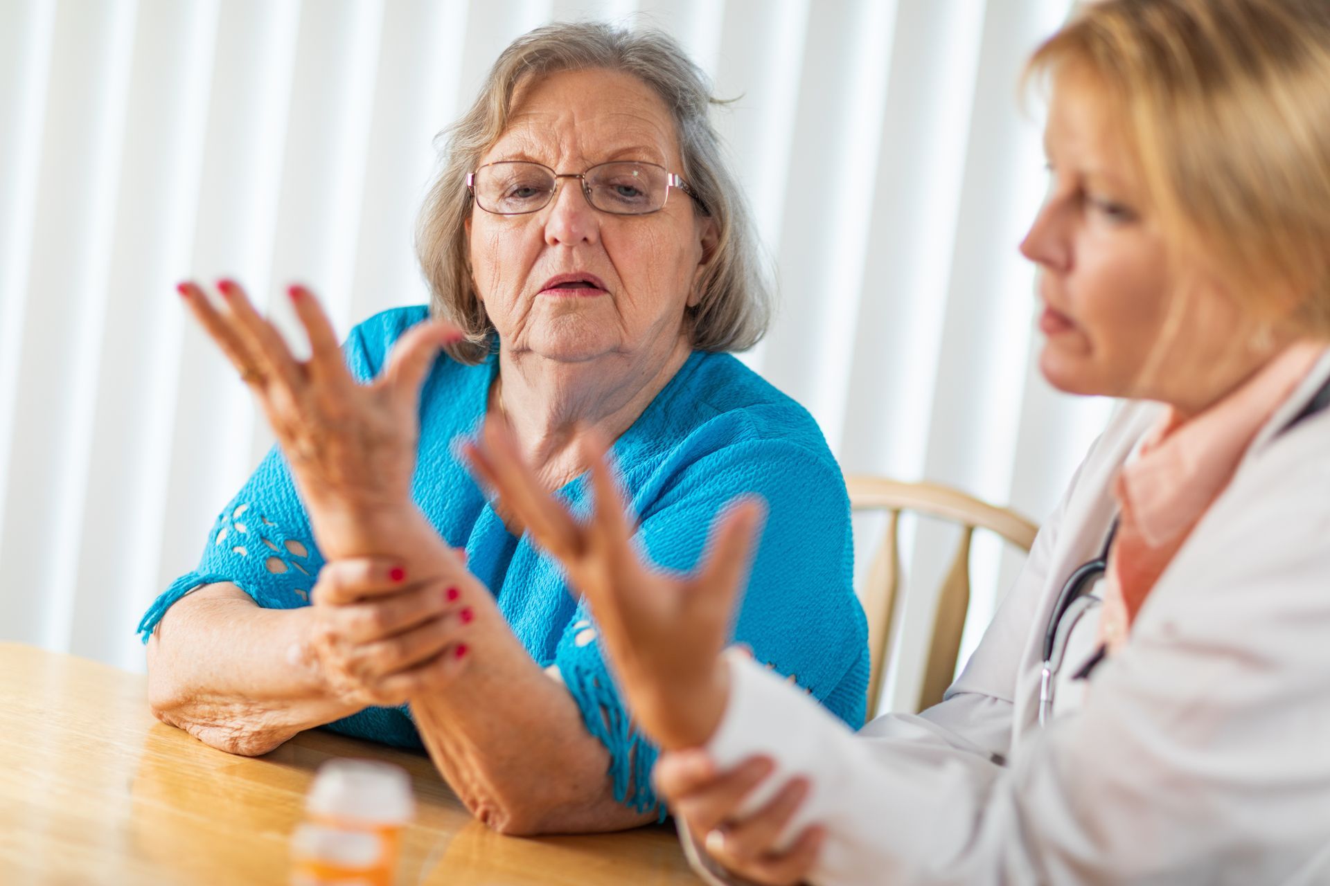Two women talking at a table, one gesturing while the other listens attentively