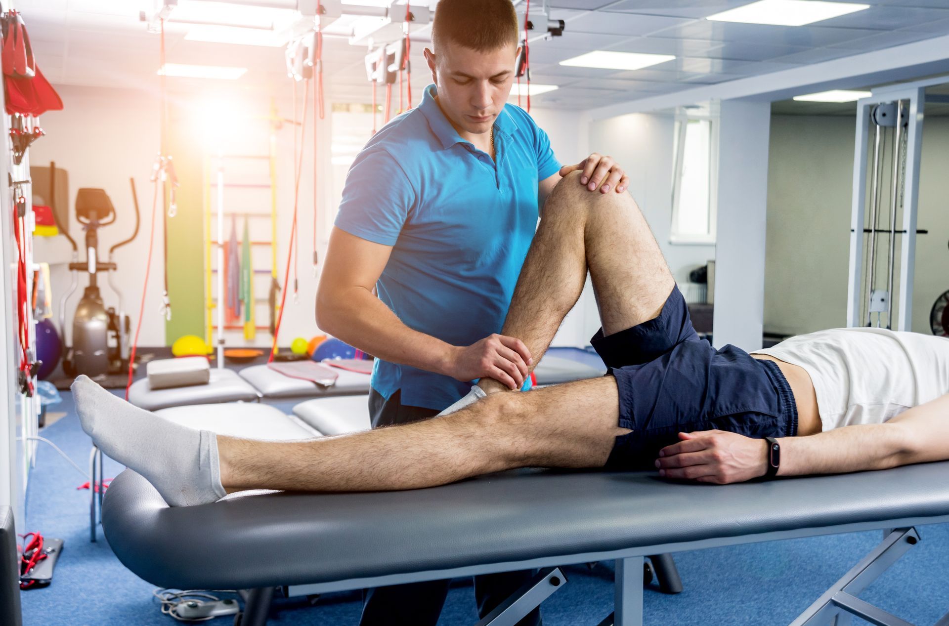 Physical therapist stretching a patient’s leg on a treatment table in a bright clinic room